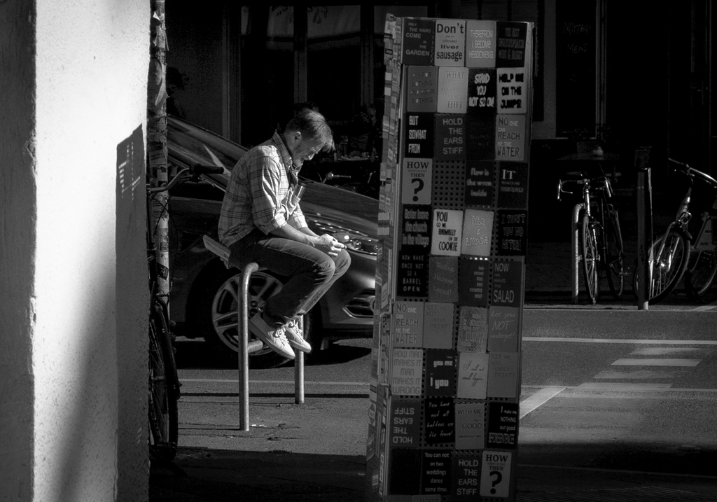 Man sitting on a post in a Berlin Street Photography shot