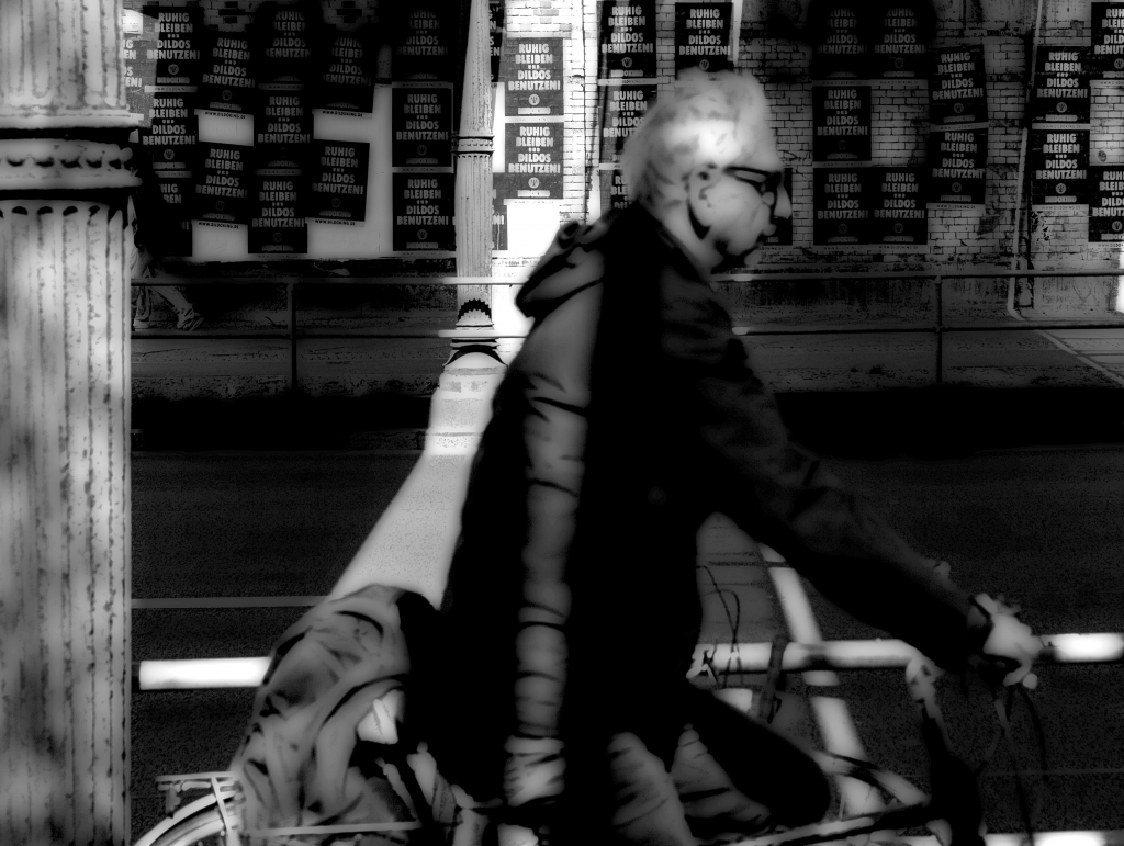 Man riding bicycle along Yorckstrasse Berlin with shadows across his face